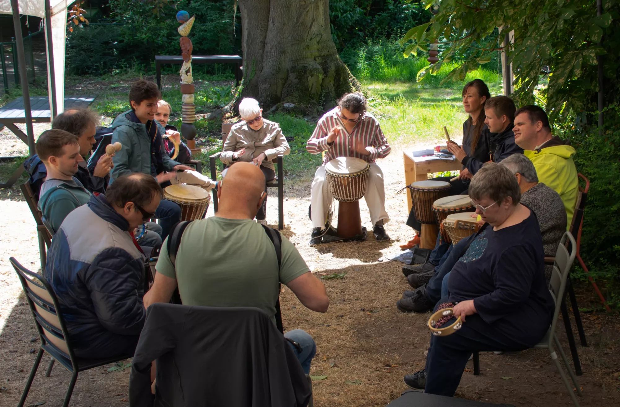 Een groep zit in een cirkel, allemaal met een instrument of trommel/djembé 