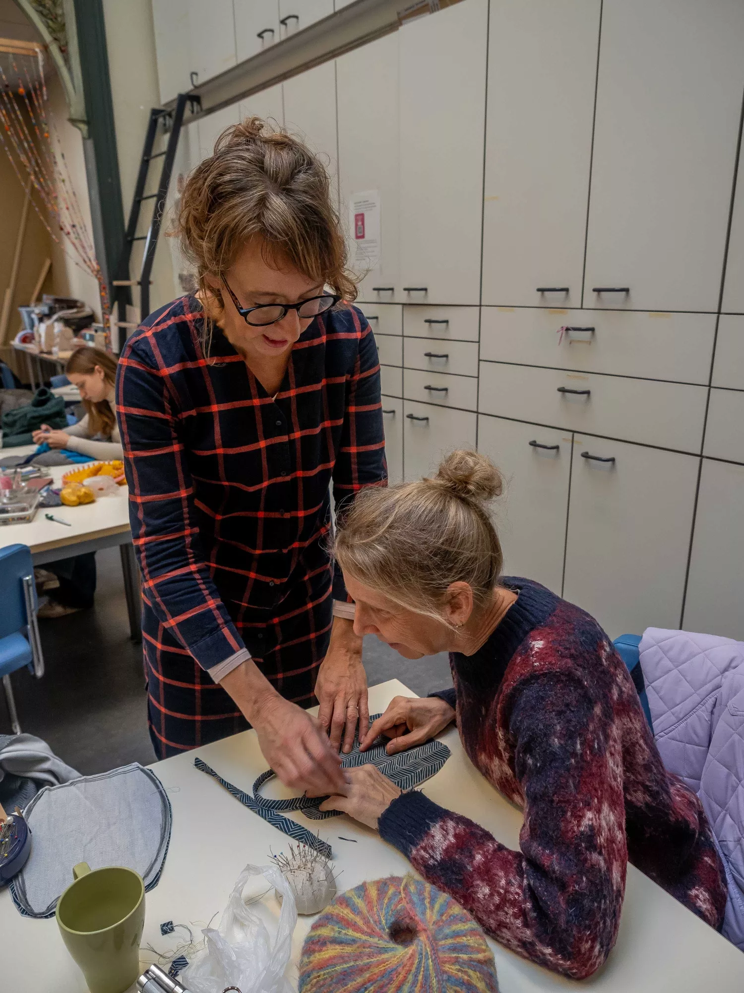 Textiel atelier Textiel atelier - vrouw krijgt ondersteuning bij het naaien