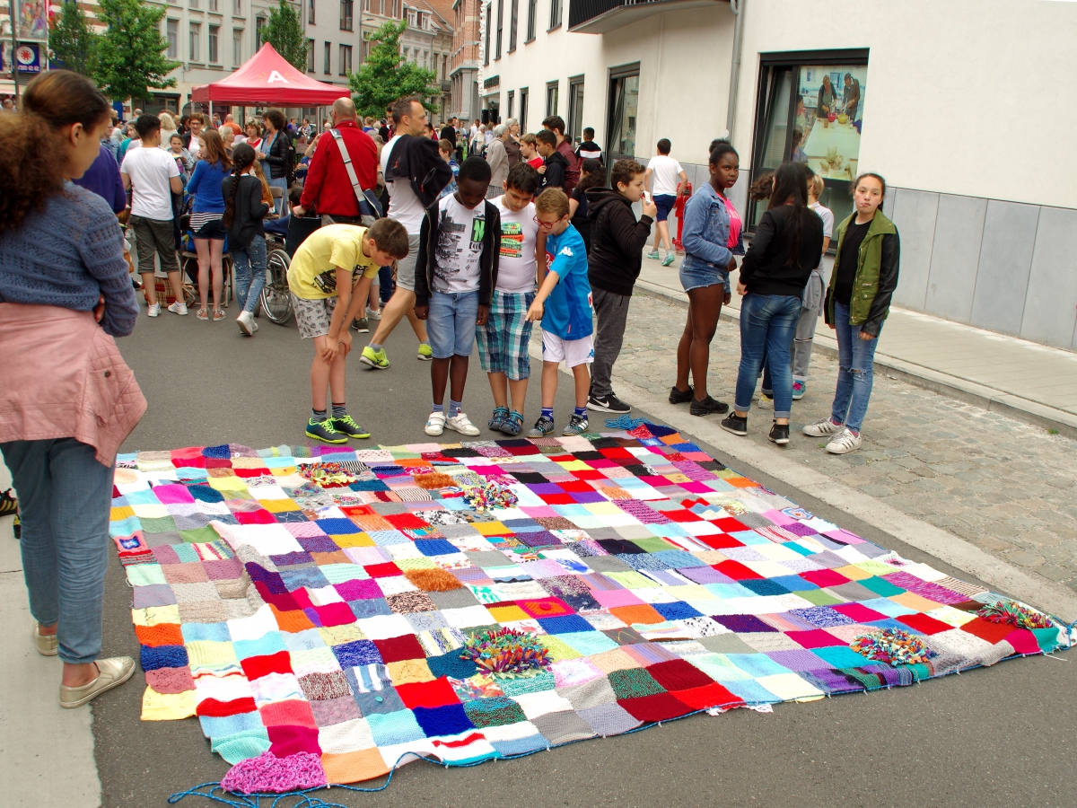 Kinderen staan rond het patchwork en wijzen hun werk aan